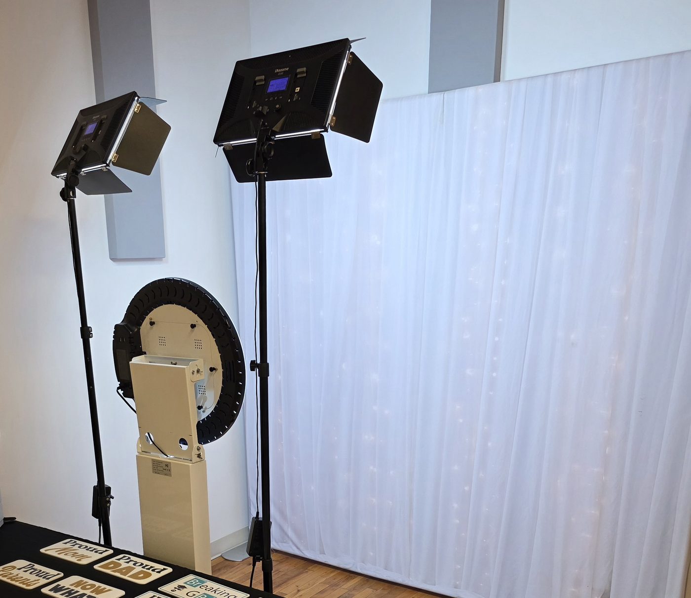 Photo booth setup with two LED panel lights raised high on stands, one on each side, above the booth