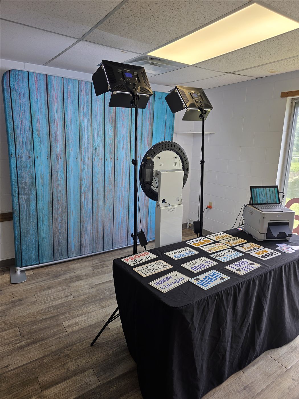 Photo booth with a teal wood backdrop, lights and a prop table