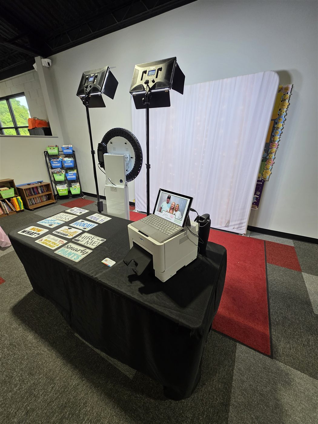 Full photo booth setup with white backdrop, video lights, ring-light booth, printer and props